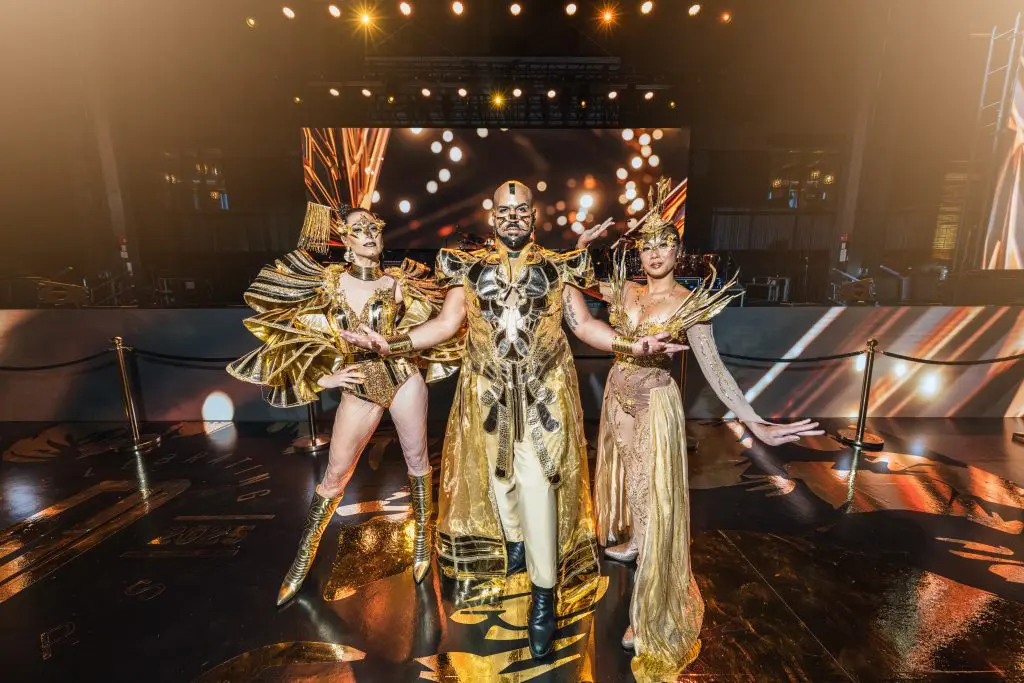 Performers in gold costumes on stage at a live event