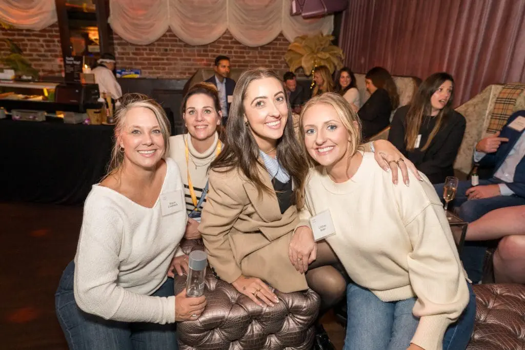 Conference attendees smile together during a networking reception at a San Francisco corporate event.
